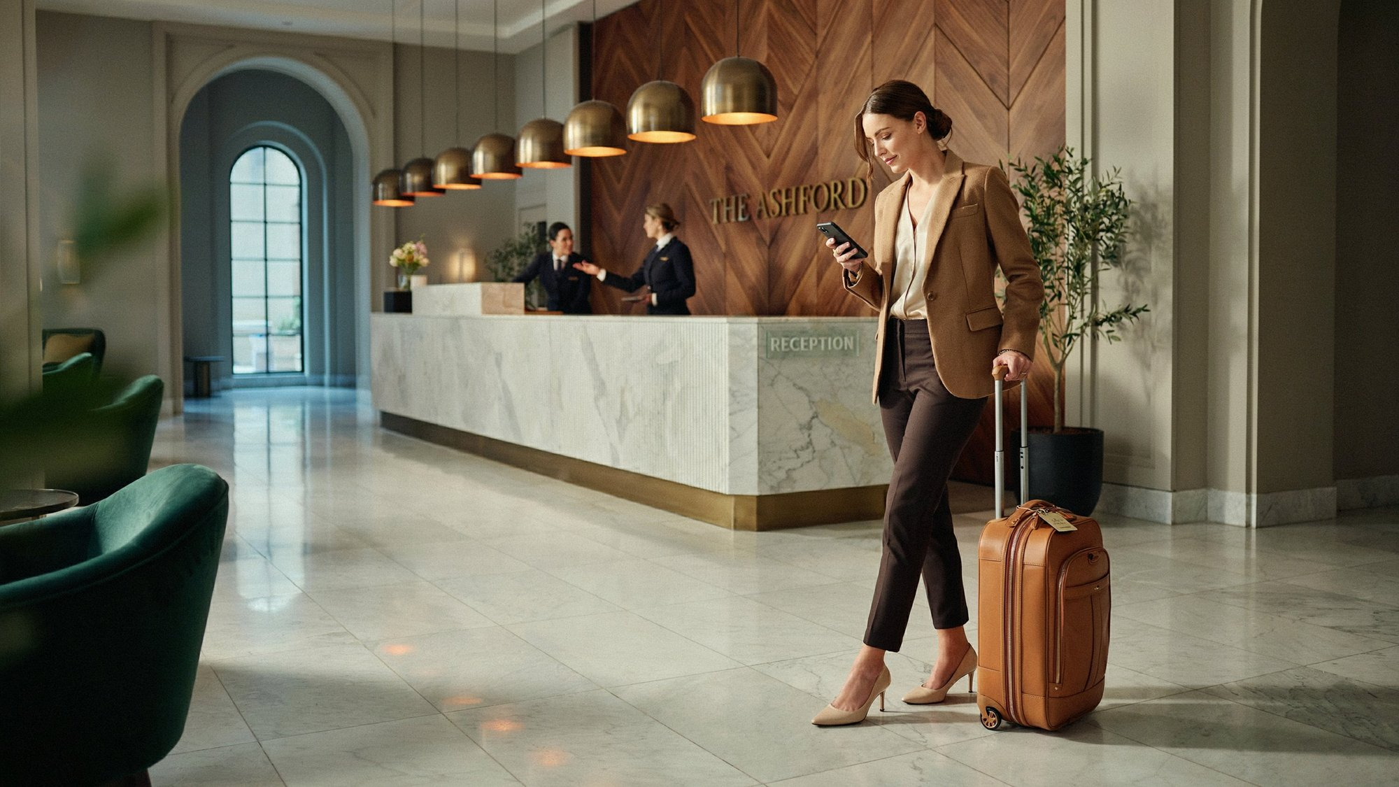 Guest checking in at a hotel reception while reviewing her phone