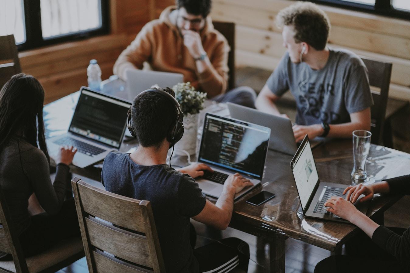 A team of CX architects collaborating around a table with laptops